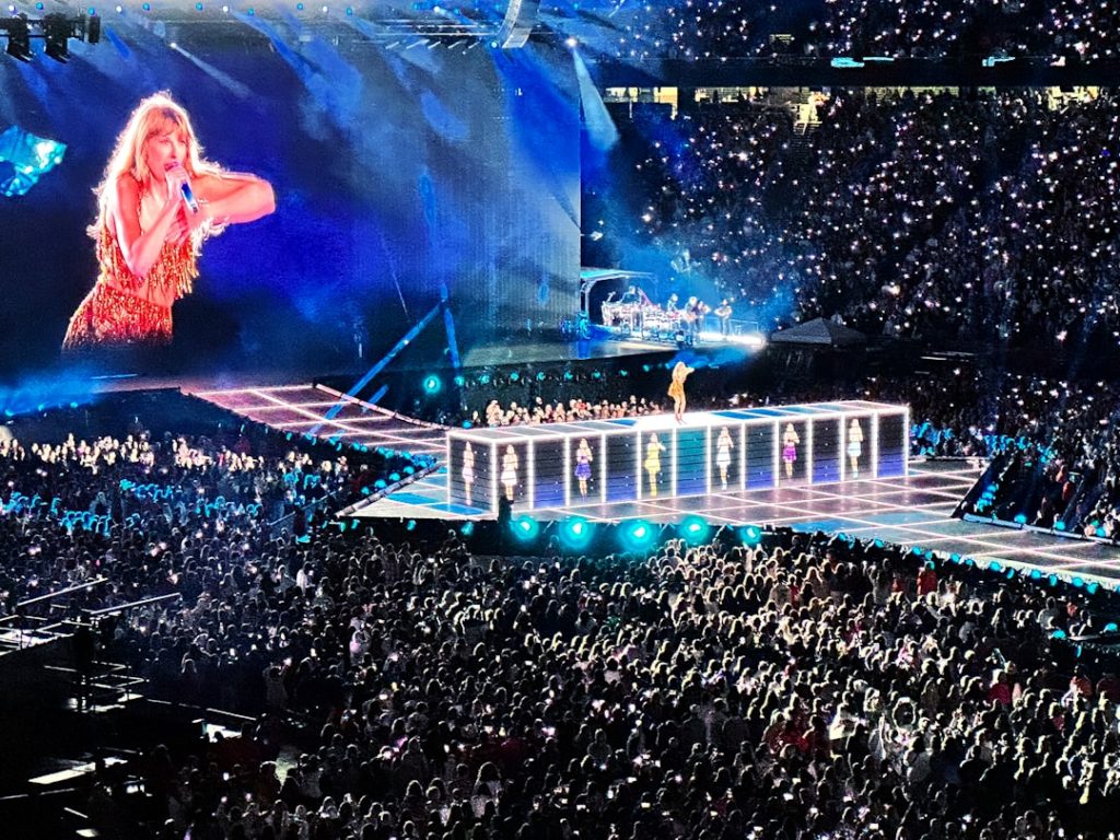 Taylor Swift en performance durante The Eras Tour, luciendo un outfit brillante y celebrando su éxito musical en 2026