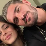 Emilia Mernes y Duki sonriendo y abrazados, mirando a cámara.